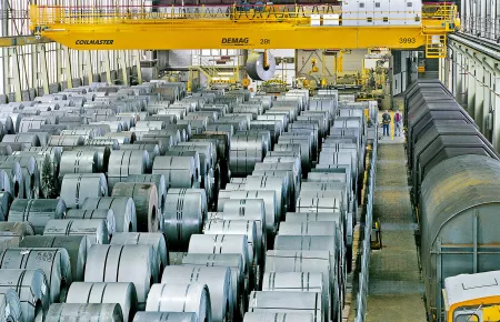 Demag Prozesskran mit Coilzange übernimmt das Handling von Stahlcoils im vollautomatisierten Rohmateriallager eines Kaltbandherstellers.